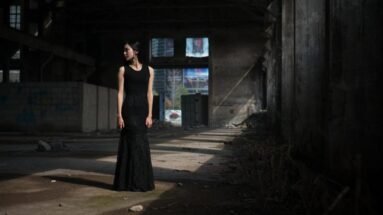 Full view of woman in long black lace gothic skirt standing in abandoned warehouse