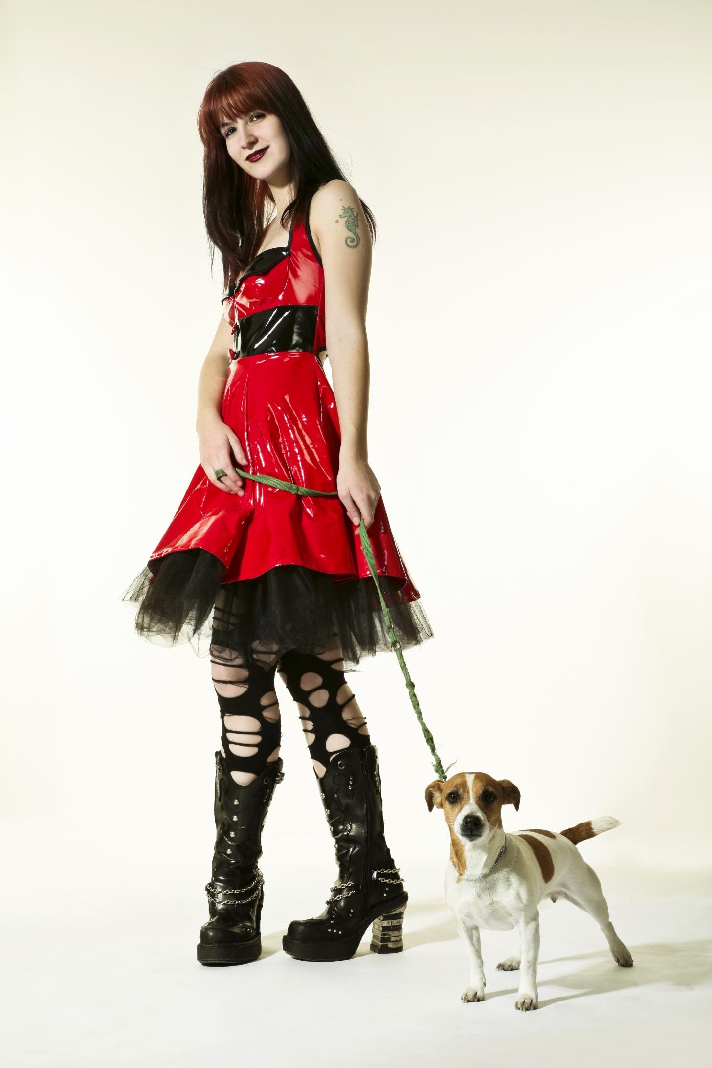 Woman in shiny red gothic dress with dog on leash, wearing ripped leggings