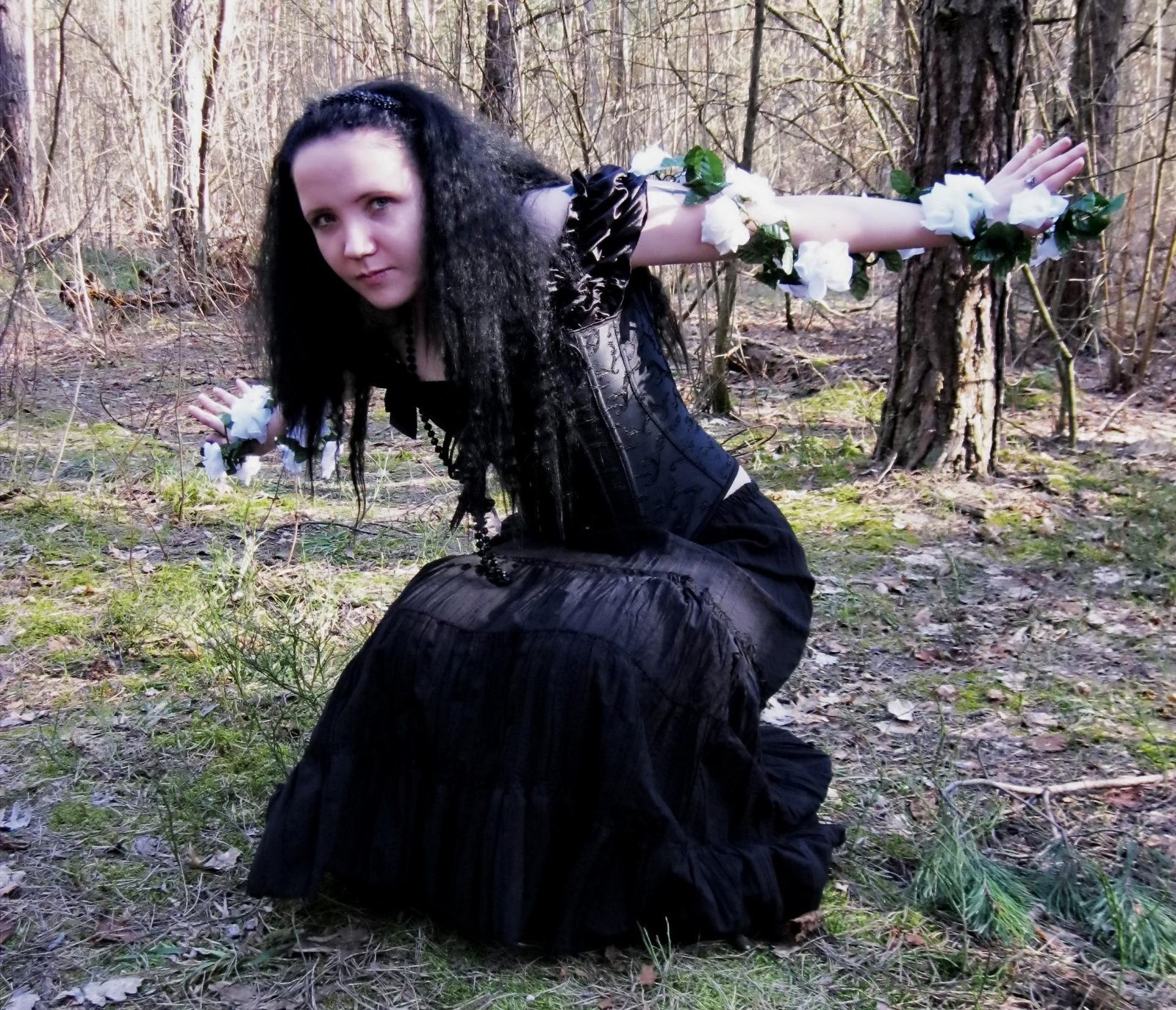 Goth woman with dark hair in a black off-the-shoulder dress, holding a glowing lantern.