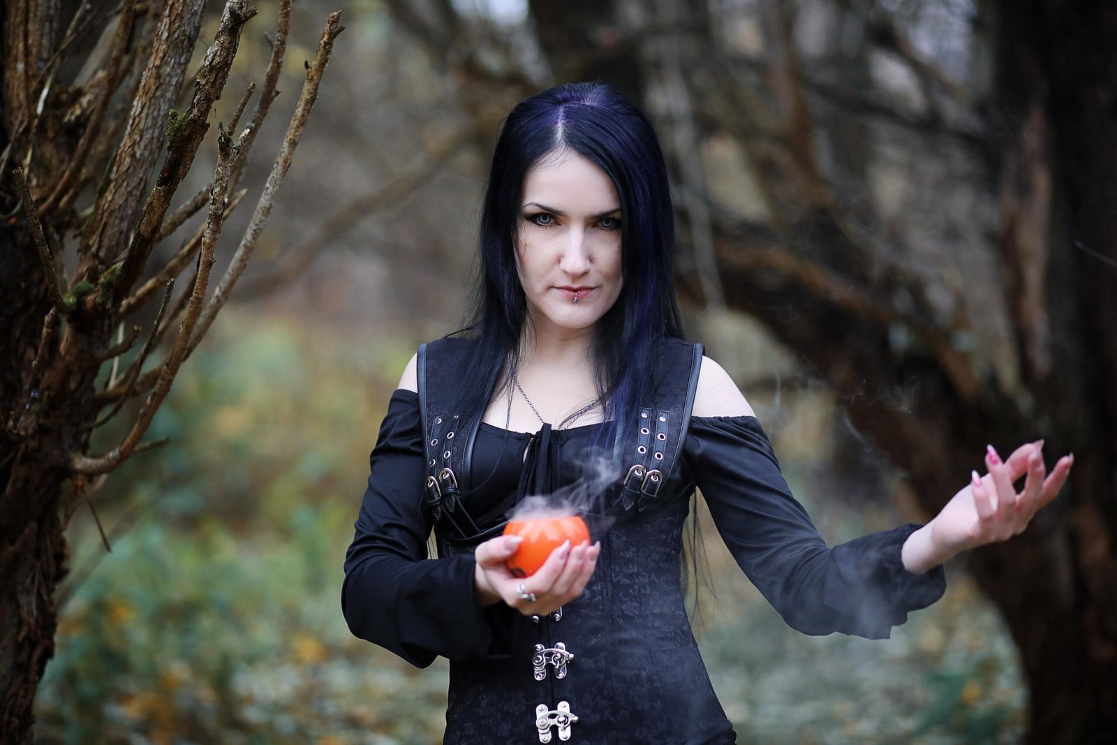 Woman in a black corset holding a smoking object, emphasizing fitted bodice and defined waistline 