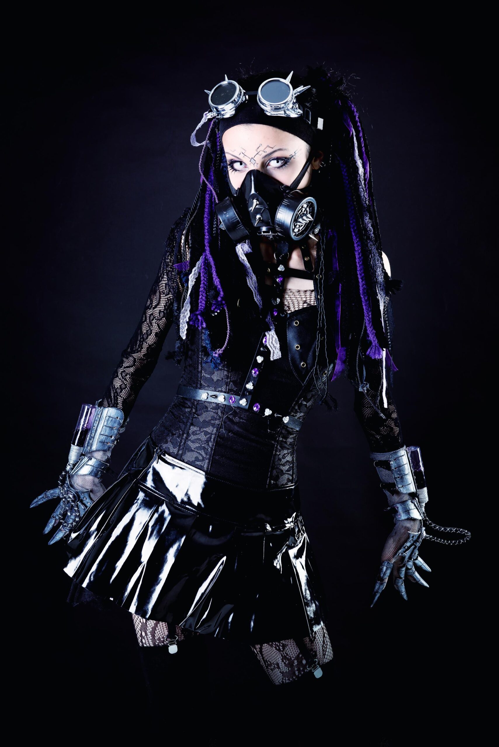 Industrial goth woman in gas mask and goggles, black latex skirt and lace top, metallic gloves, purple dreadlocks, dramatic studio lighting.