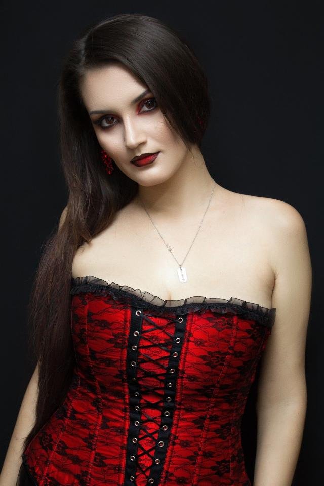 Red and black lace corset worn against a dark background, showcasing lace texture, boning, and front lacing