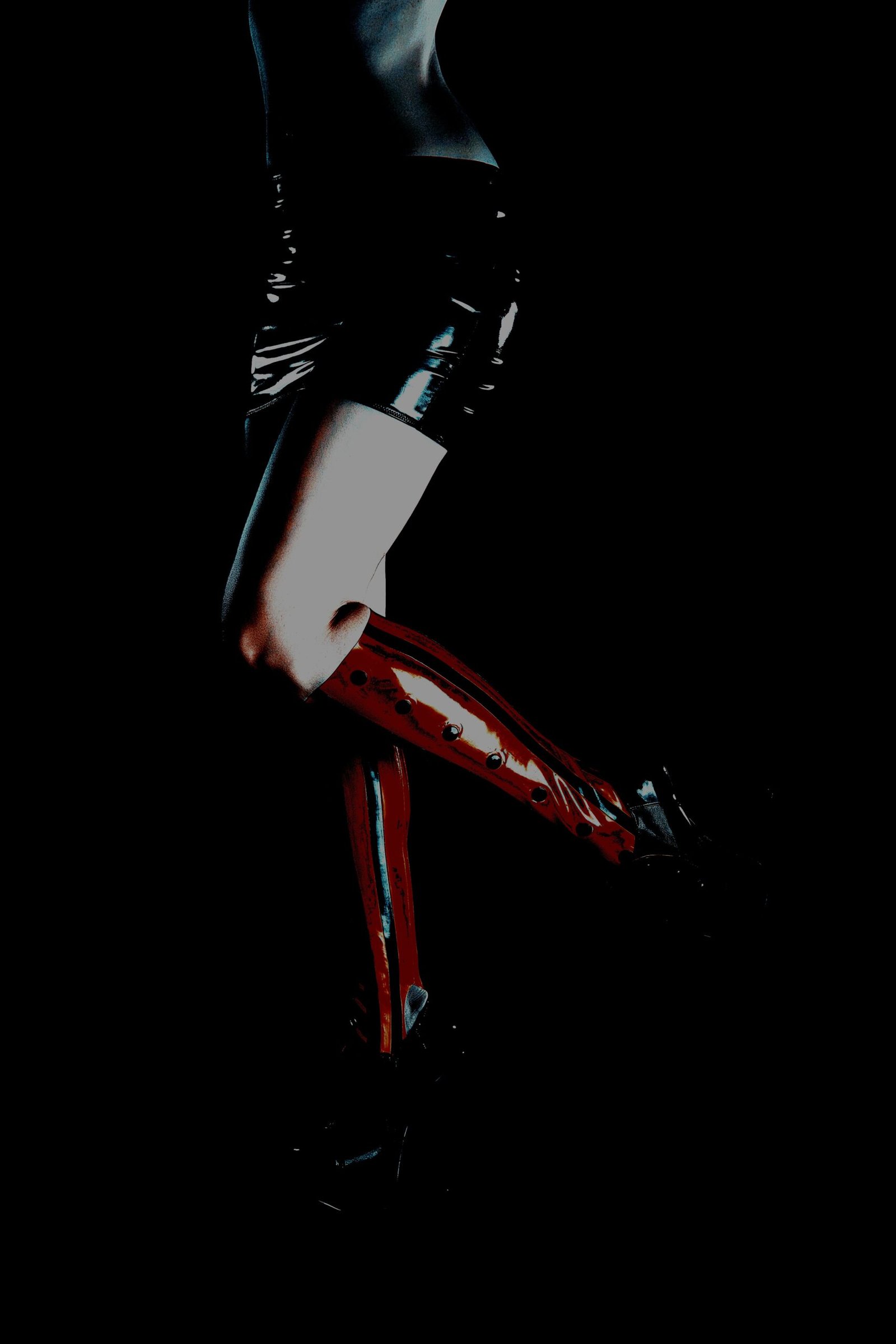 Moody silhouette of person in high heels and glossy outfit with dramatic contrast lighting