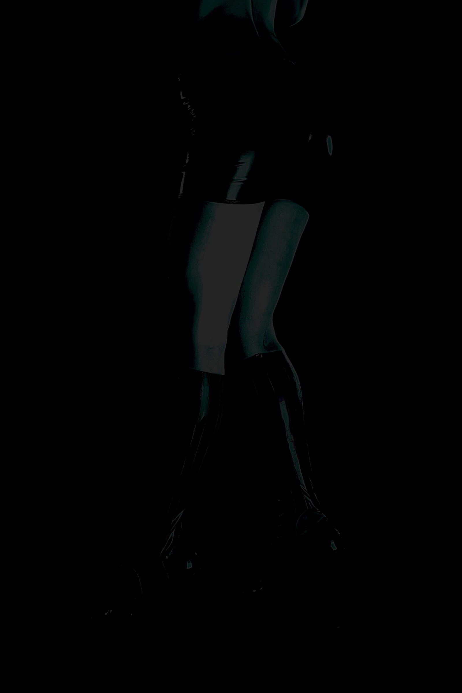 Low-key silhouette of person in thigh-high boots and short outfit, dramatically lit against a dark background